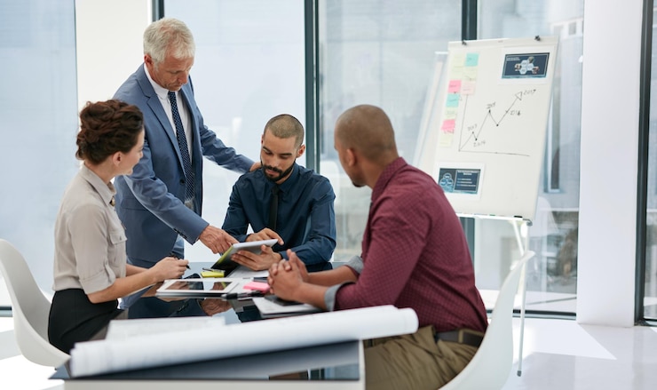 A team meeting in a glass-walled office with a whiteboard