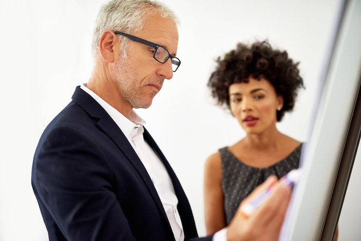 Two colleagues discussing a plan at a whiteboard