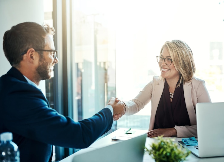 Two people shaking hands across a desk